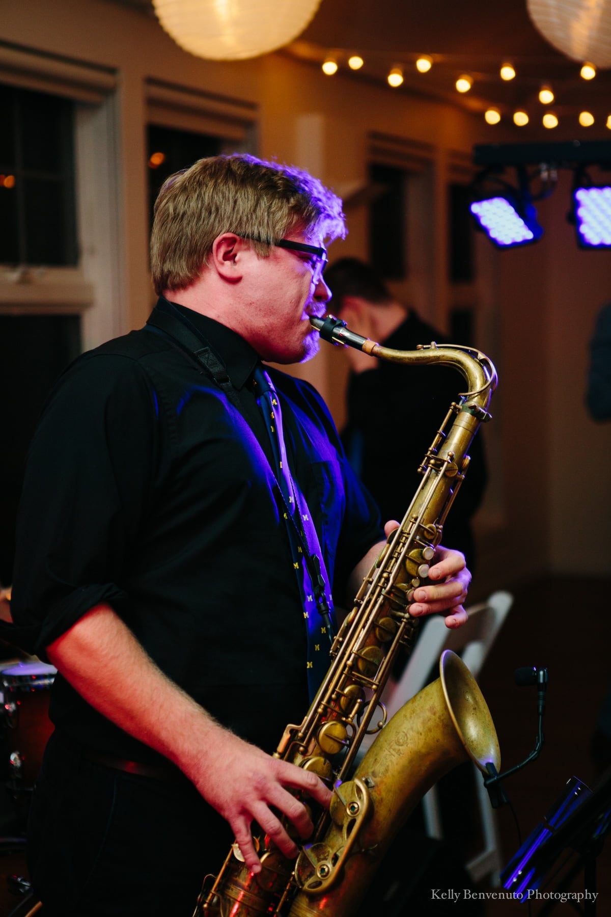Jazz saxophonist performing passionately under warm lights at an intimate live indoor concert.