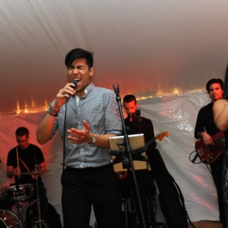 Live band performing under warm string lights at a Boston wedding reception.