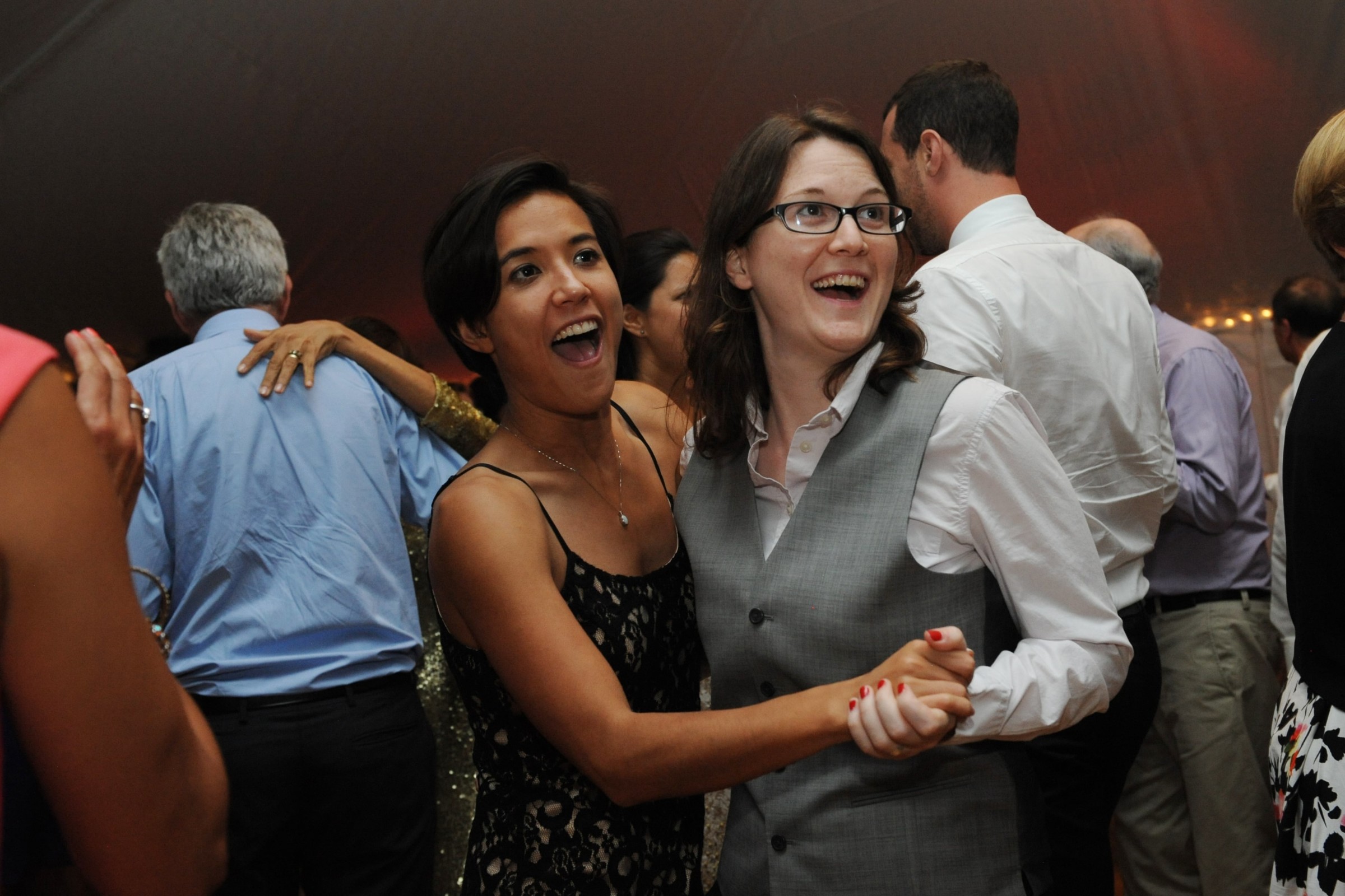 Two women dancing joyfully at a lively Loring Greenough House wedding in Boston.
