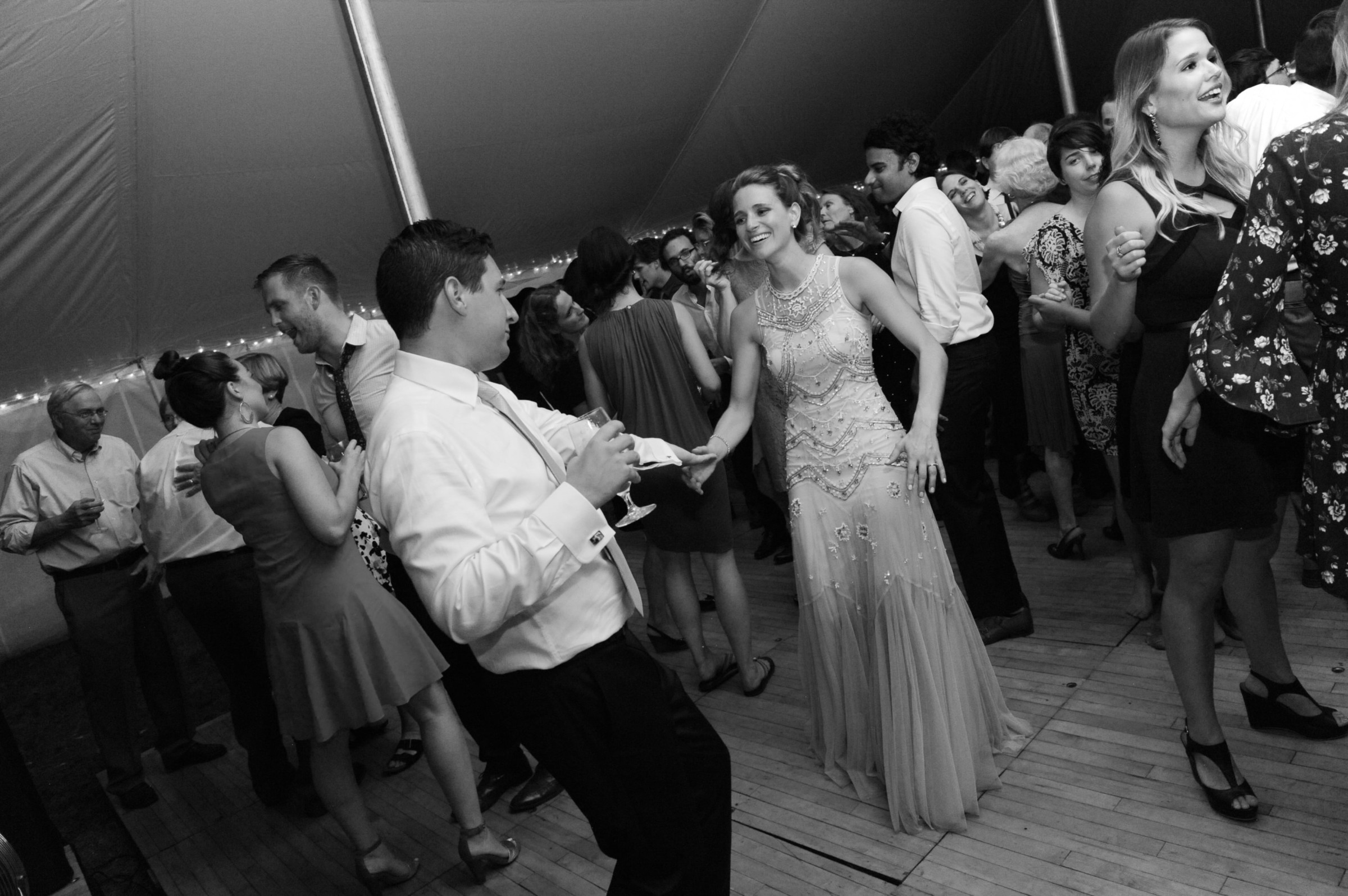 Elegant black-and-white photo of guests dancing under a glowing tent at a Boston wedding.
