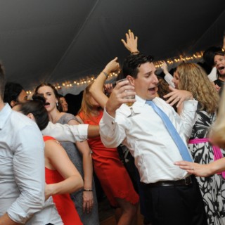 Guests dancing and celebrating under warm string lights at a lively Boston wedding reception.