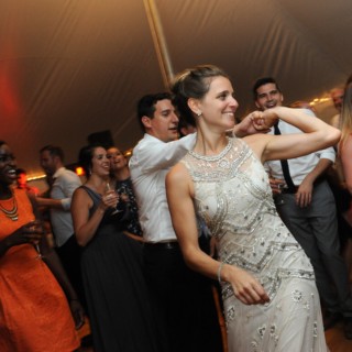 Bride dancing joyfully under a glowing tent at Loring Greenough House wedding in Boston.