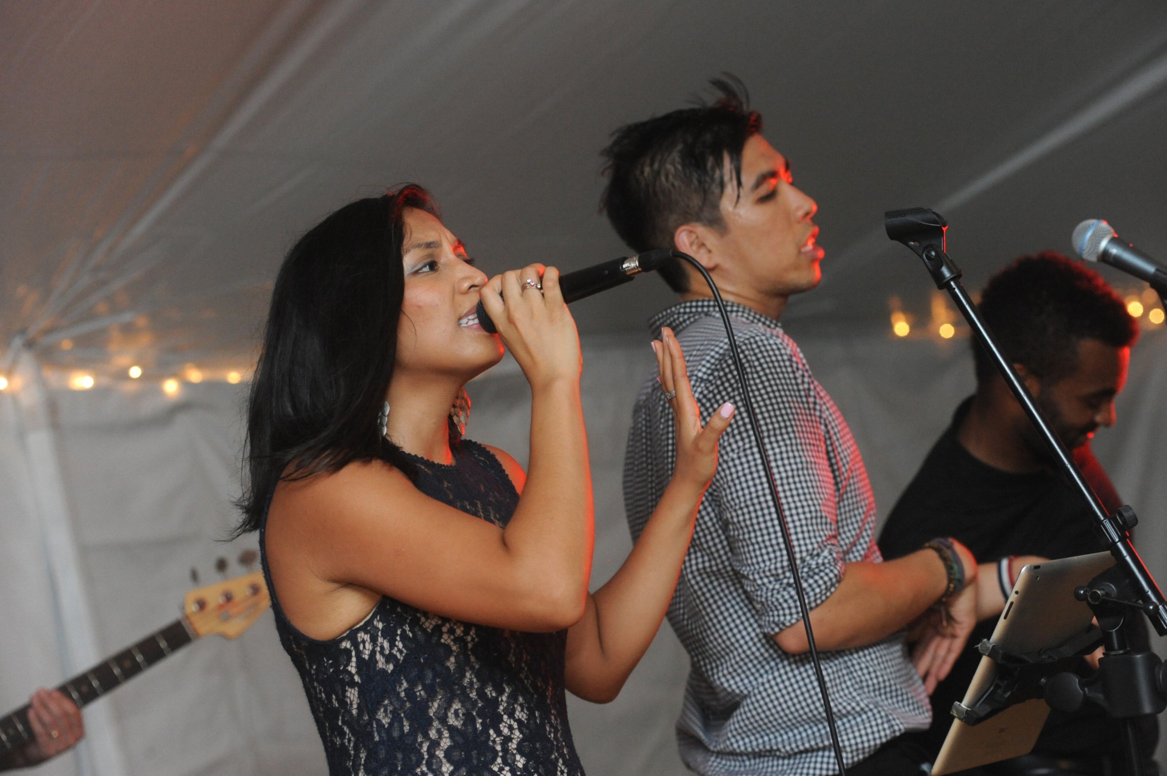 Live music duo performing under warm string lights at a Boston outdoor wedding.
