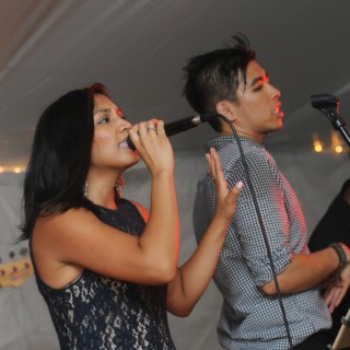 Live music duo performing under warm string lights at a Boston outdoor wedding.