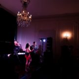 Live band performing at elegant Glen Manor House with female singer under warm chandelier lighting.