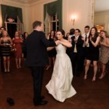 Bride and groom share a romantic first dance in an elegant, golden-lit ballroom.