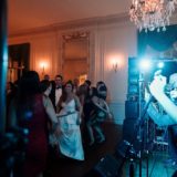 Bride and guests dancing at elegant Glen Manor House wedding reception with live band and chandeliers.