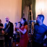 Elegant indoor wedding band with female singer, male vocalist, and saxophonist performing live.