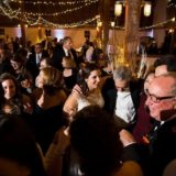 Bride and guests laughing and dancing under warm string lights at Gedney Farm wedding.