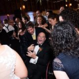 Guests cheering around a laughing man in a wheelchair at a joyful Gedney Farm wedding.