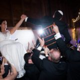Bride and groom lifted during joyful Hora dance at rustic Gedney Farm wedding celebration.