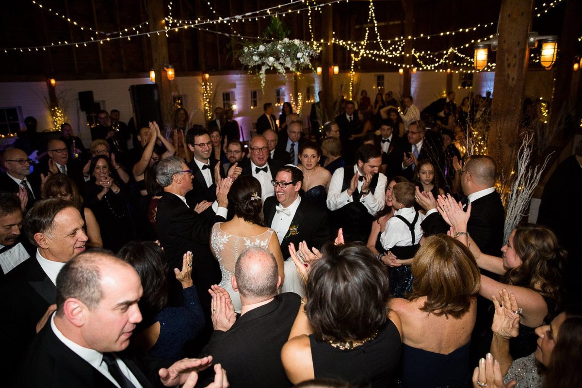 Bride and groom celebrating joyful barn wedding at Gedney Farm under warm glowing lights.