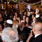 Bride dancing with guests under warm string lights at Gedney Farm wedding in Massachusetts.