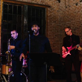 Live jazz band performing in a cozy urban loft with warm lighting and rustic brick walls.