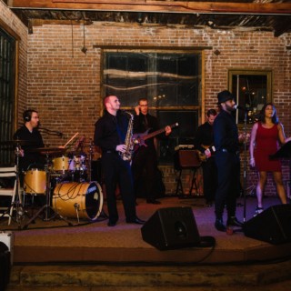 Live band performing on rustic stage with warm lighting and brick walls in New York City.