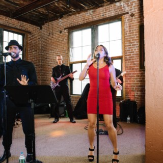 Live band performing in rustic New York venue with exposed brick walls and warm lighting.