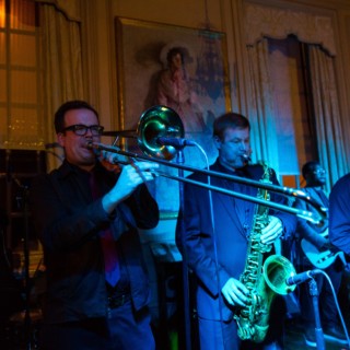 Jazz band performing live in elegant indoor venue with warm and cool stage lighting.