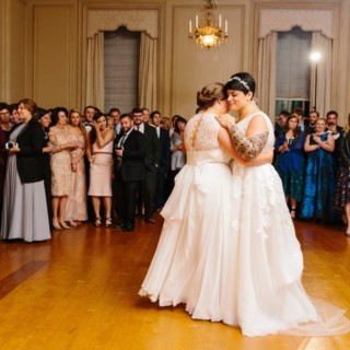 Two brides share a romantic first dance in an elegant ballroom at Crane Estate wedding.