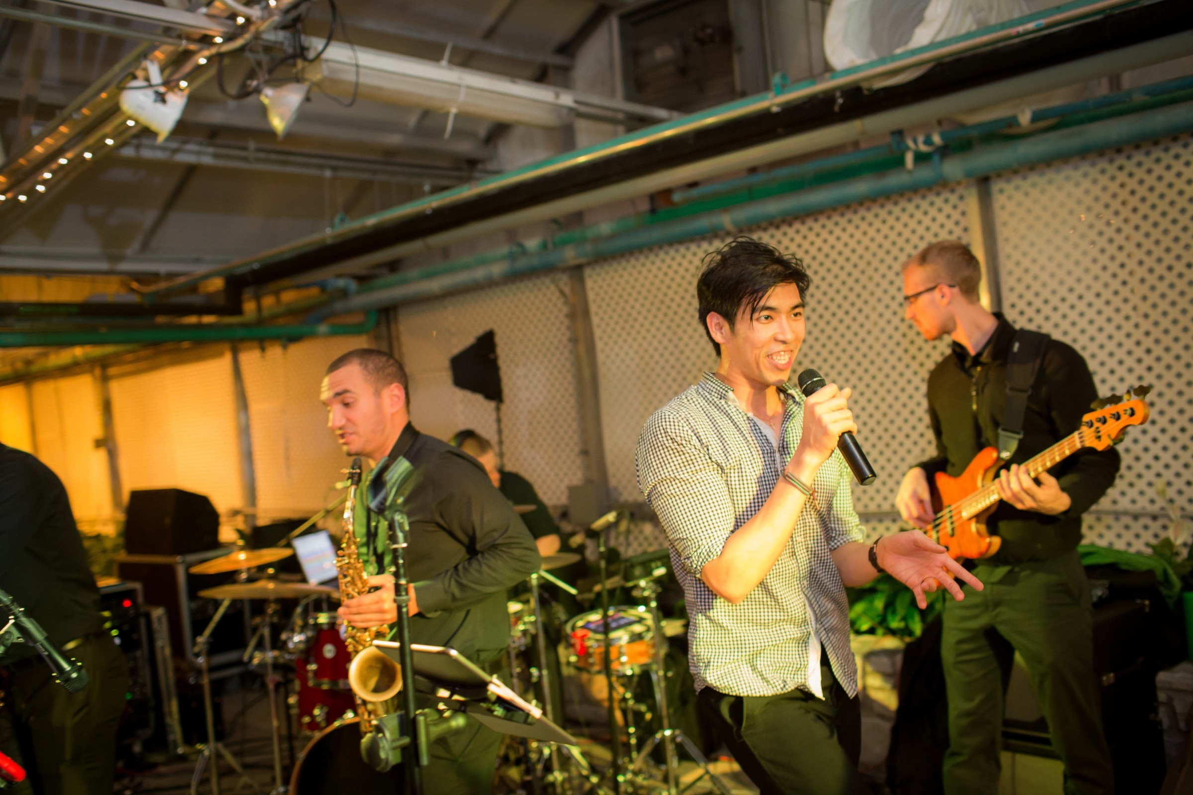 Live band performing indoors with singer, saxophonist, and bassist at Philadelphia event.