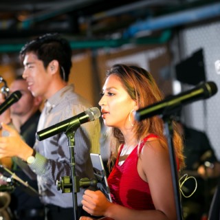 Trio of vocalists performing live with passionate energy under warm stage lighting in Philadelphia venue.