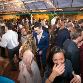 Bride and groom celebrating with guests under glowing string lights at Fairmount Park Horticulture Center.