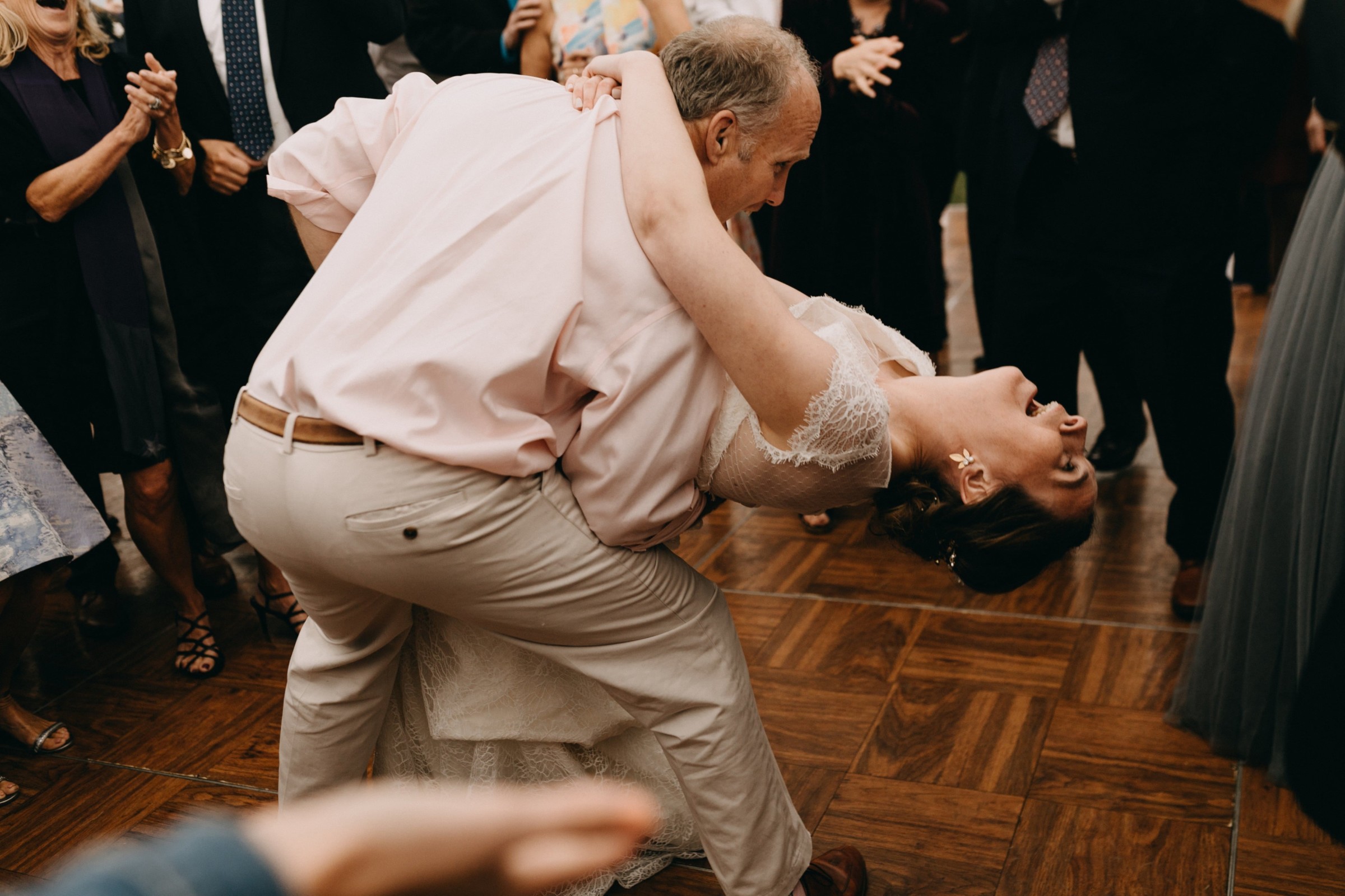 Bride laughing as her father dips her during a joyful wedding dance in Newbury, Massachusetts.