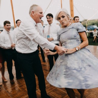 Older couple dancing joyfully at outdoor wedding under string lights in Newbury, Massachusetts.