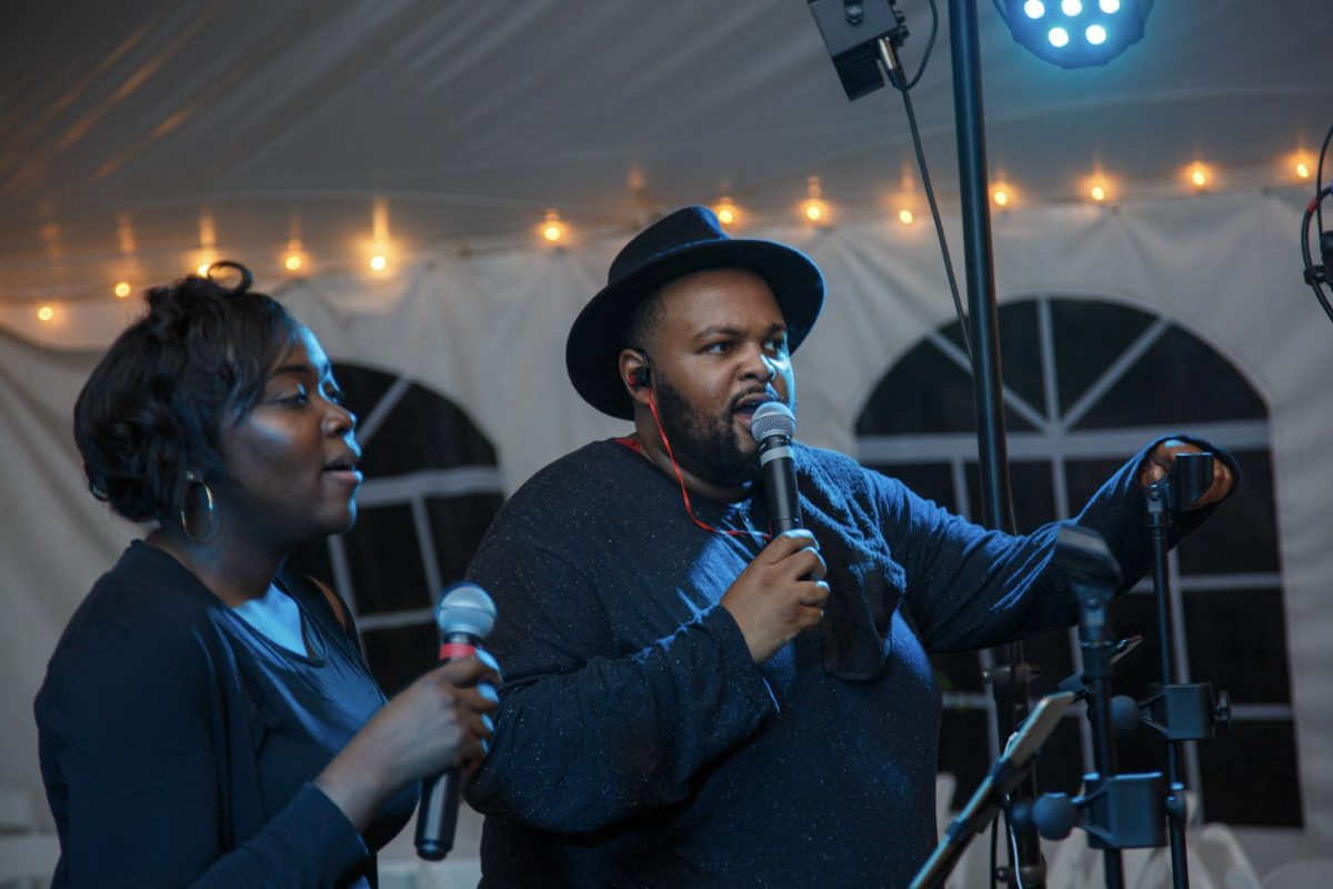 Man and woman singing live duet under warm string lights at Waterville Valley wedding.