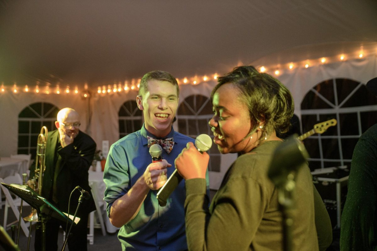 Smiling duo singing under warm lights at Waterville Valley wedding celebration.