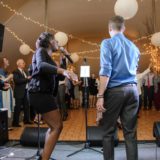 Bride singing with guests dancing under fairy lights at Waterville Valley wedding reception.