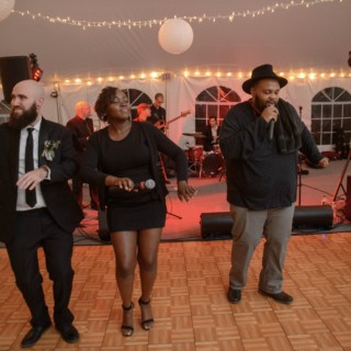 Guests dancing and singing under string lights at a lively Waterville Valley wedding celebration.