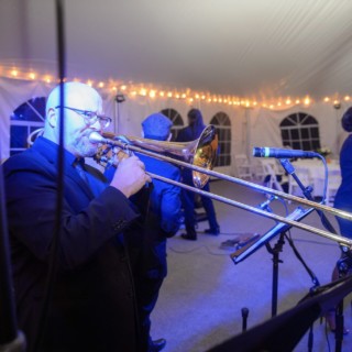 Jazz band performing under warm string lights inside an elegant evening tent in Waterville Valley.