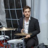 Young drummer in black suit performing live at elegant Waterville Valley wedding reception.