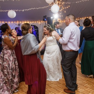 Bride dancing with guests under glowing tent lights at lively Waterville Valley wedding reception.