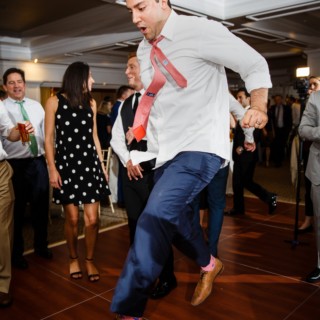 Man jumping mid-dance at lively Willowbend Country Club wedding reception in Mashpee, Massachusetts.