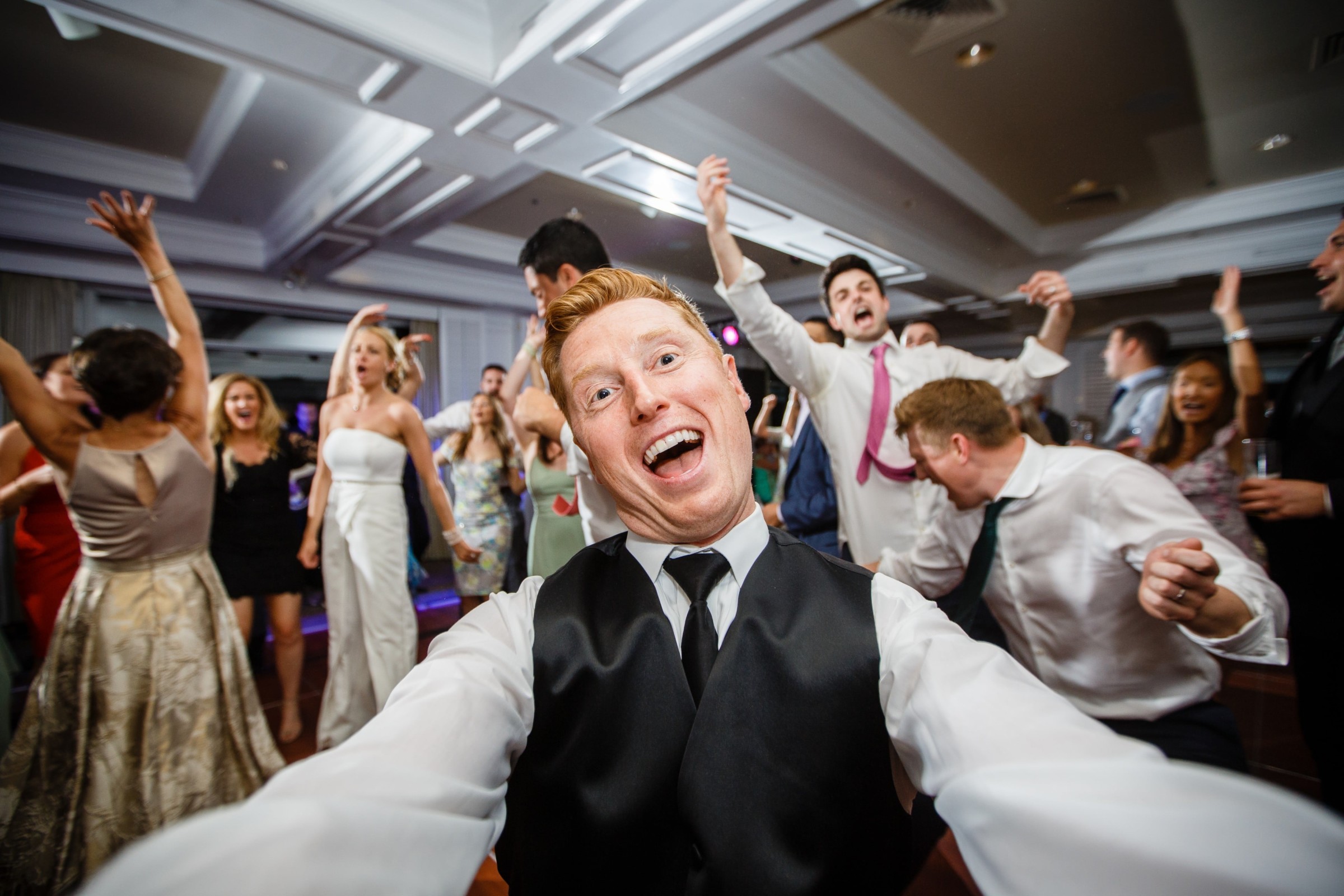 Red-haired guest taking a joyful selfie during a lively wedding reception at Willowbend Country Club.