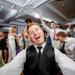 Red-haired guest taking a joyful selfie during a lively wedding reception at Willowbend Country Club.