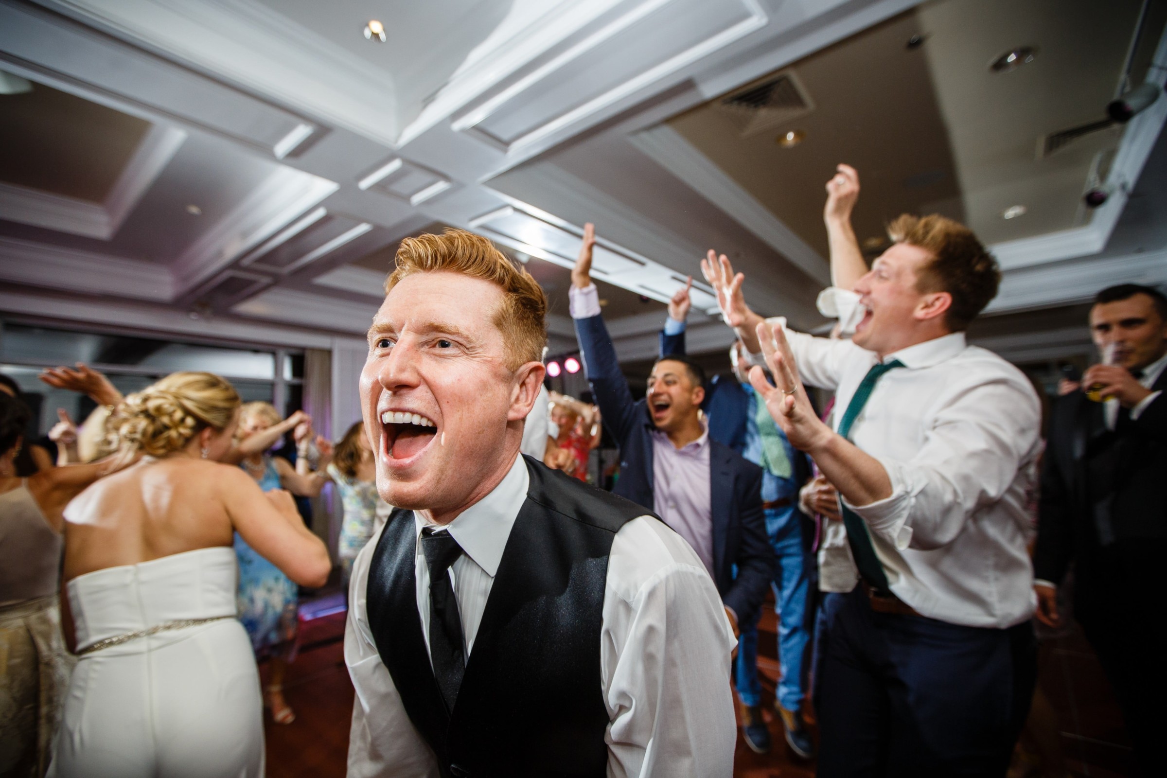Groom laughing and dancing with guests at a lively Willowbend Country Club wedding reception.