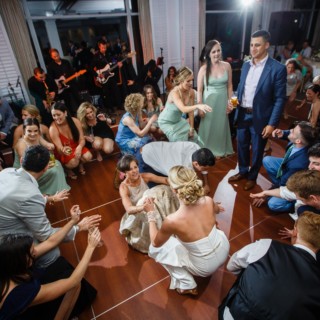 Bride dancing joyfully surrounded by guests at lively Willowbend Country Club wedding reception.