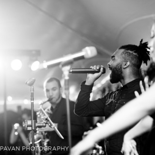 Black and white photo of passionate live band performance with vocalist and saxophonist on stage.