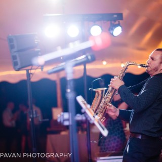 Saxophonist performing live under warm lights at a festive outdoor wedding in Newport, Rhode Island.