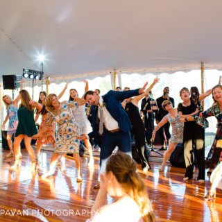 Guests dancing joyfully under a white tent at a lively Newport Rhode Island wedding celebration.
