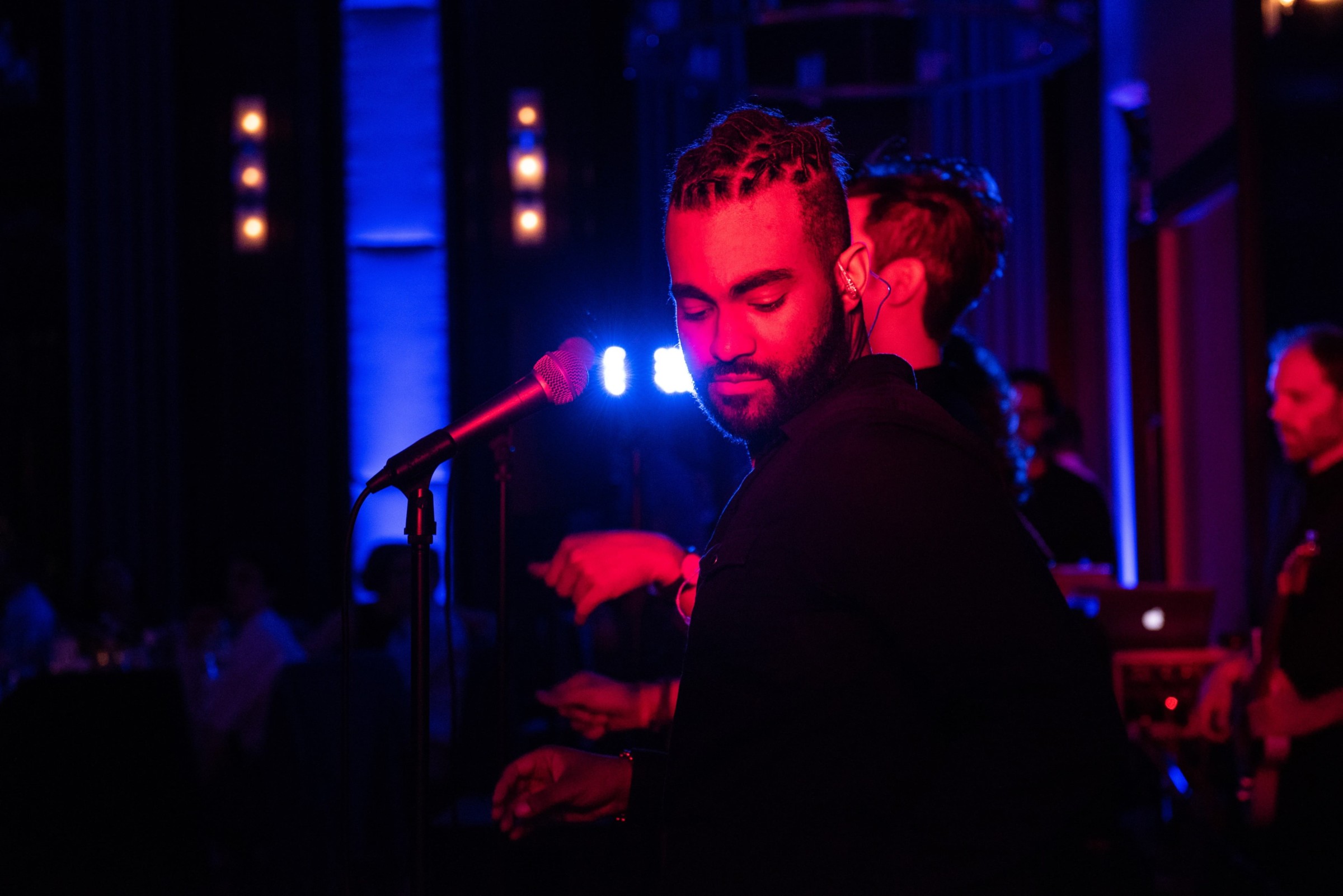 Singer performing under pink and blue stage lights at an intimate Boston wedding venue.