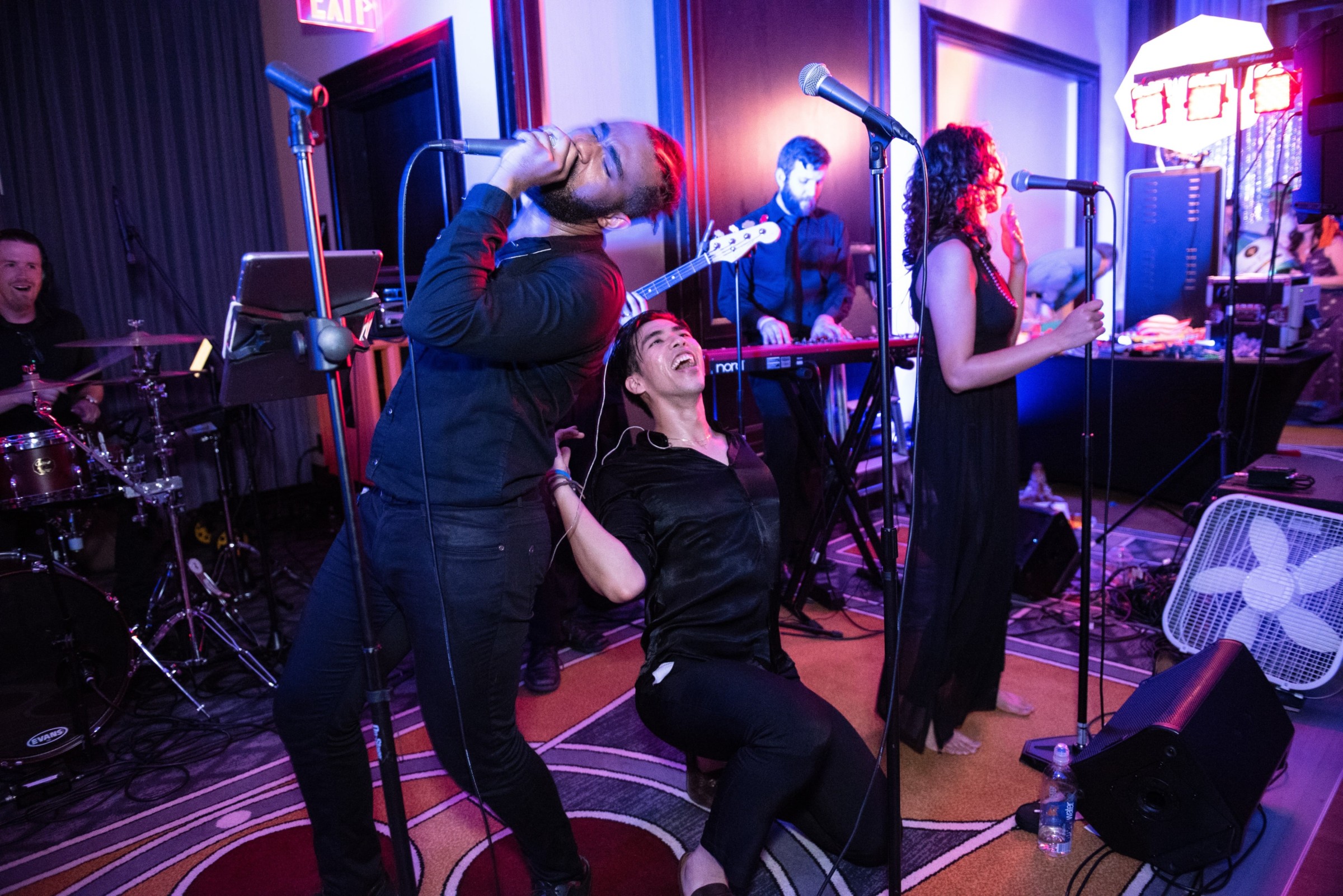 Vibrant live wedding band performing at Boston’s Liberty Hotel under colorful stage lights.