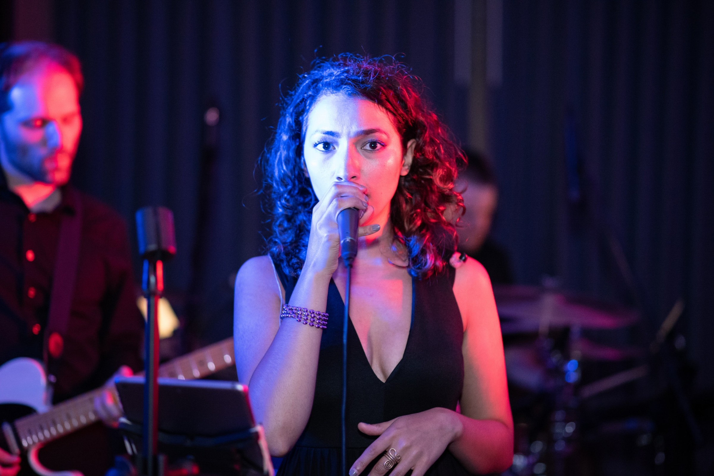 Female singer performing live on stage under vibrant blue and magenta lights.