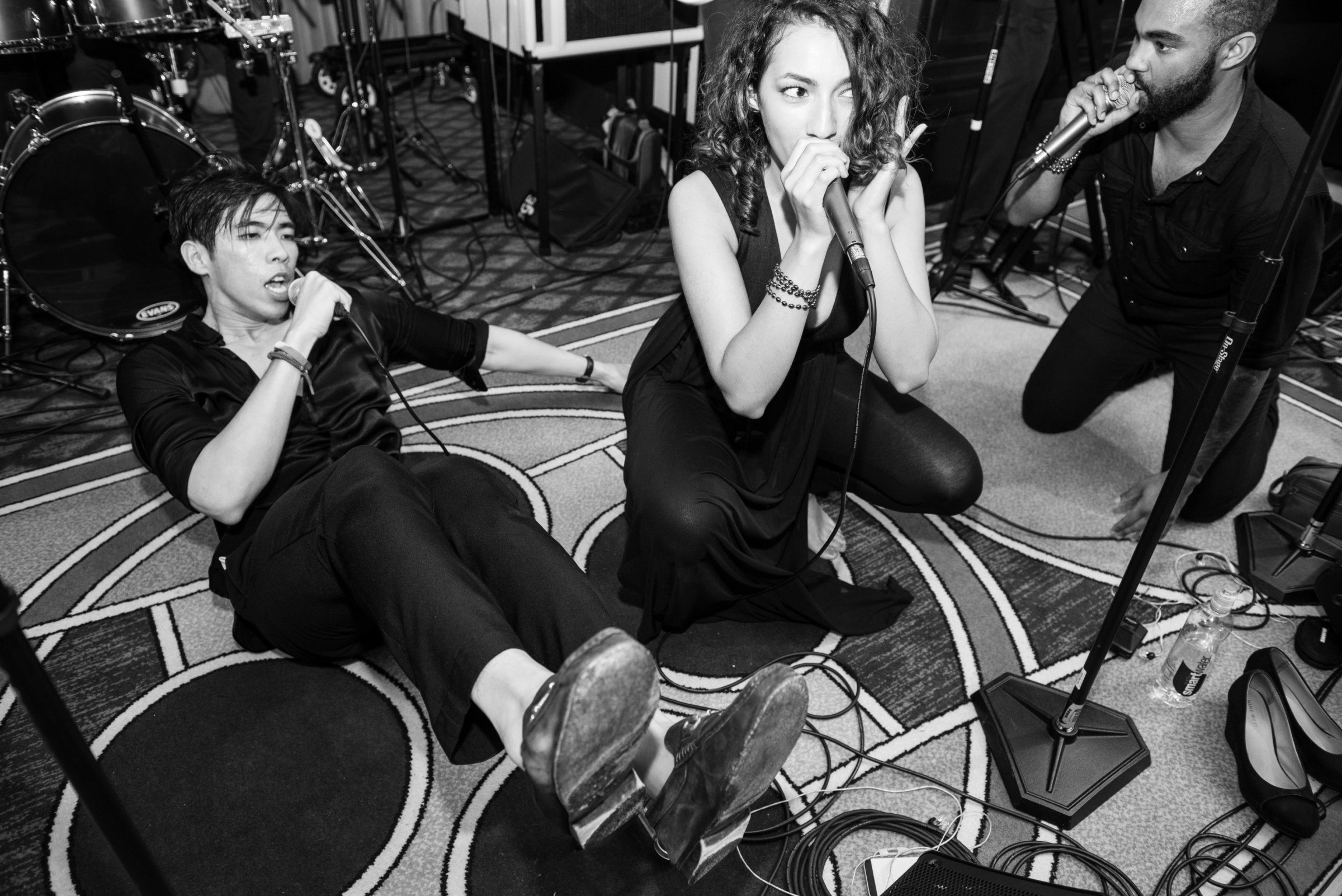 Three passionate singers performing together in an emotional black-and-white live music scene.