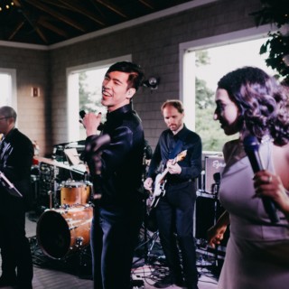 Live band performing at a Thompson Island wedding in Boston with singers and lush natural backdrop.
