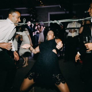 Guests enjoy a playful limbo game during a lively Thompson Island wedding reception in Boston.