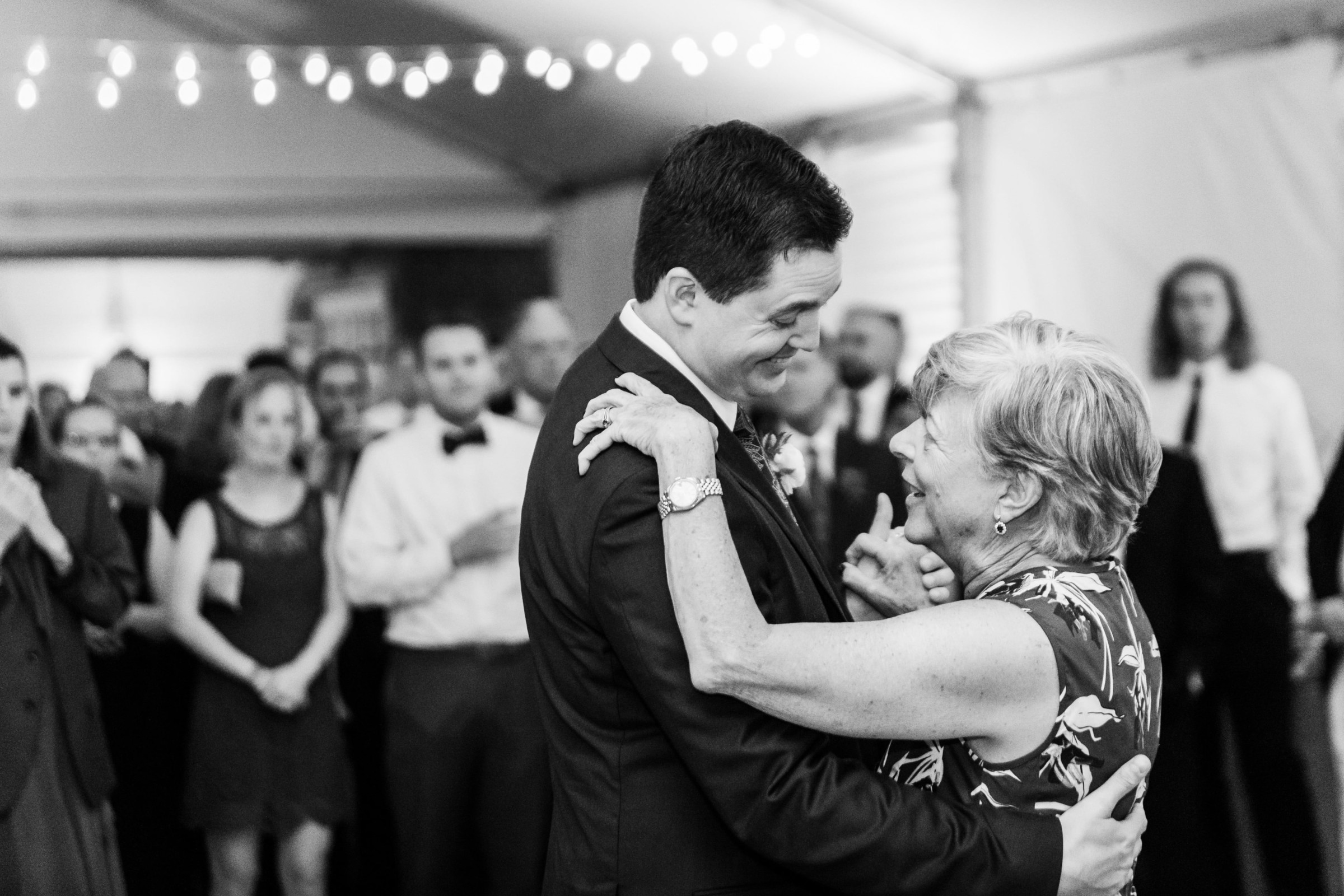 Groom dancing with his mother under string lights at Elm Bank wedding in Wellesley, Massachusetts.