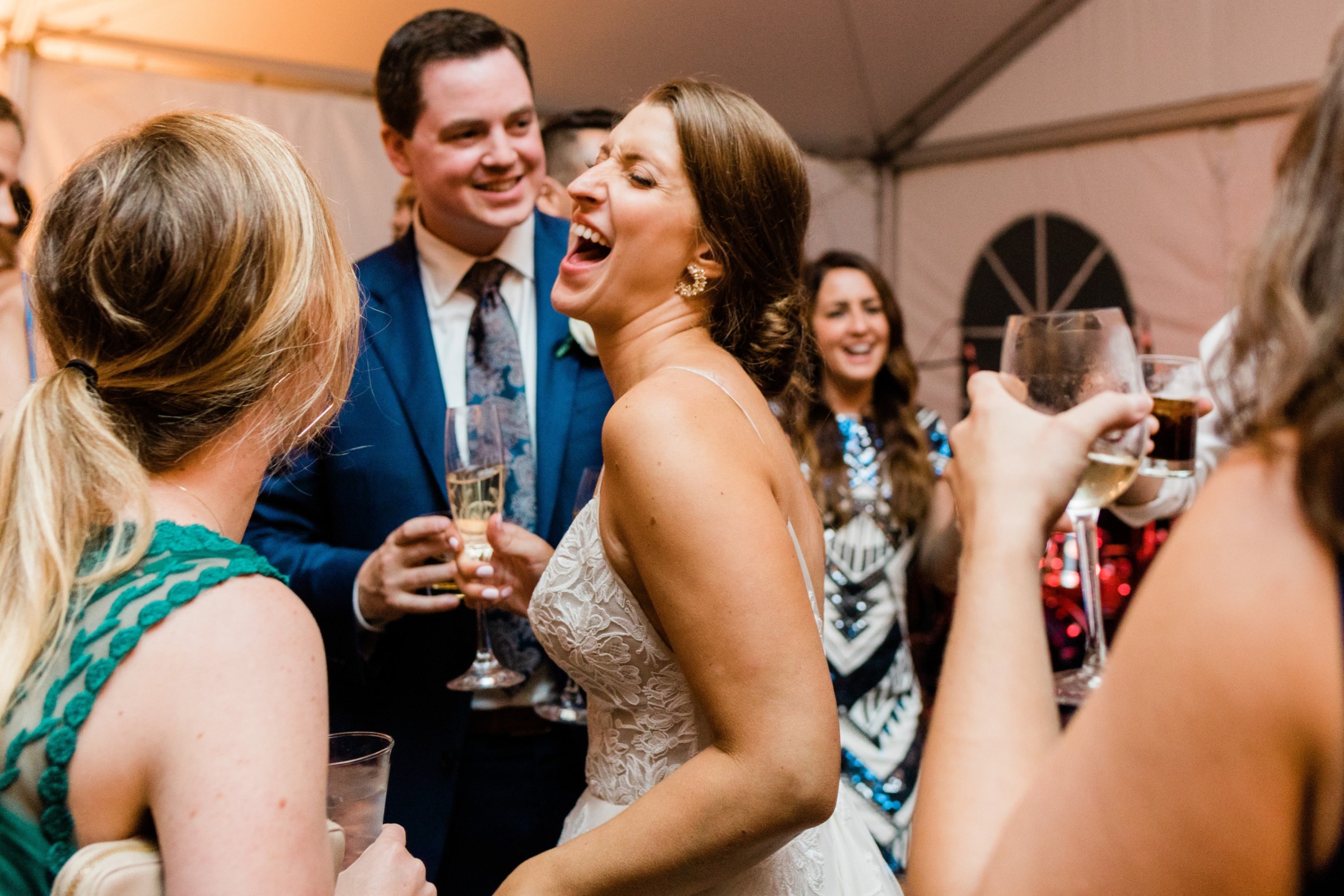 Bride and groom laughing with guests during joyful Elm Bank wedding reception in Wellesley, Massachusetts.